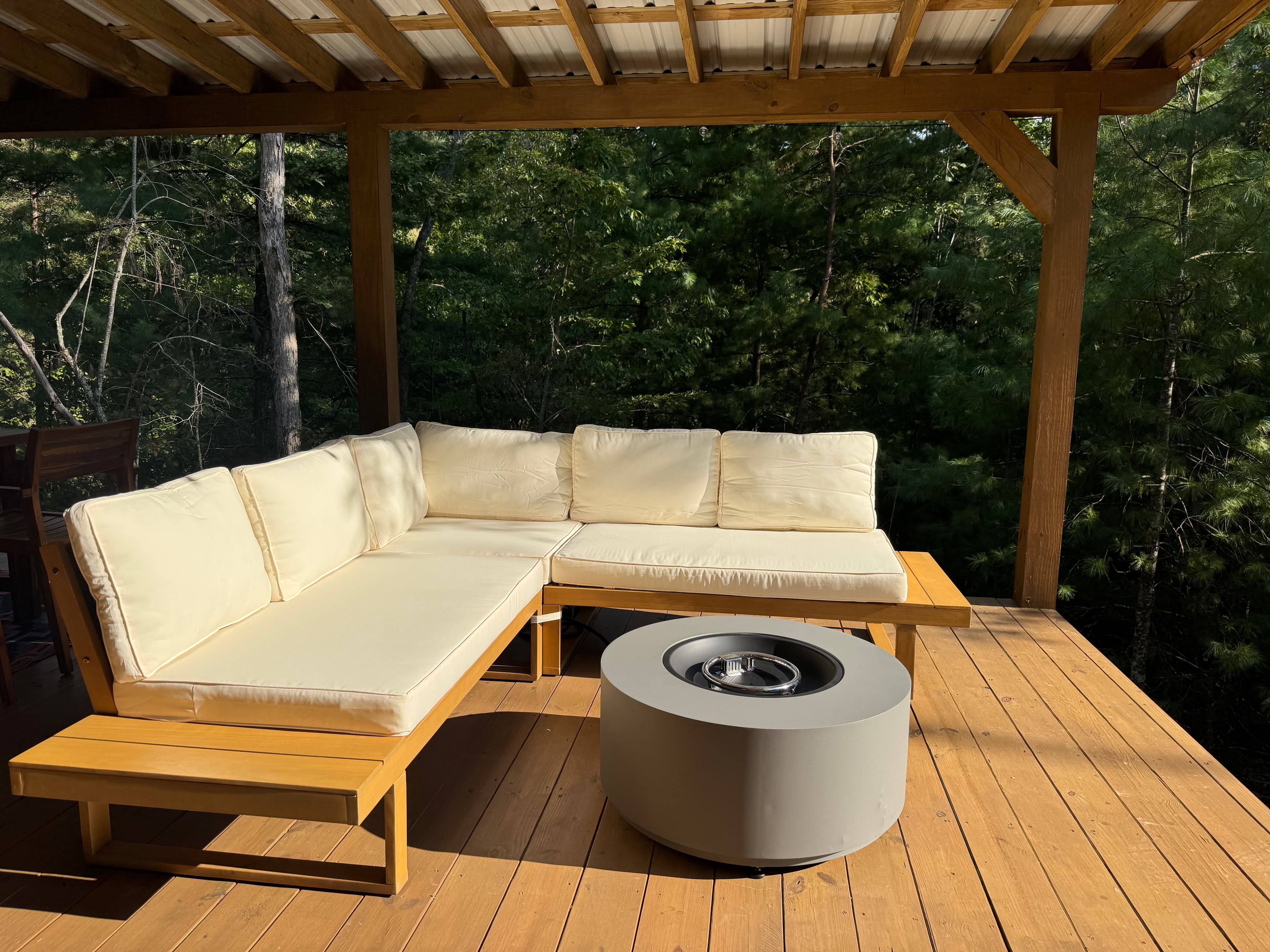 Covered deck lounge with sectional sofa and fire pit under a cedar pergola