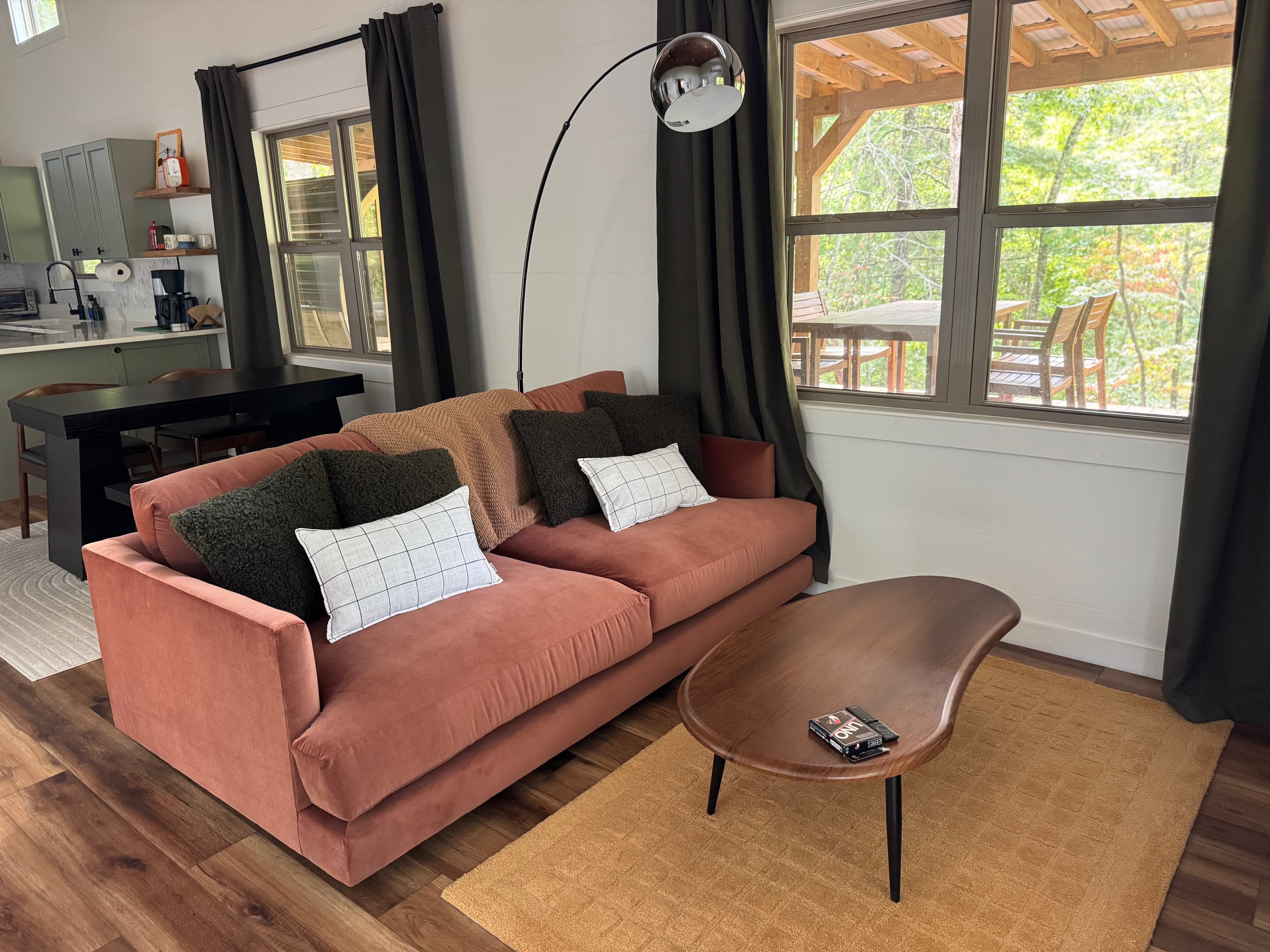 Living room with rust sofa, walnut coffee table, and arched black-framed windows