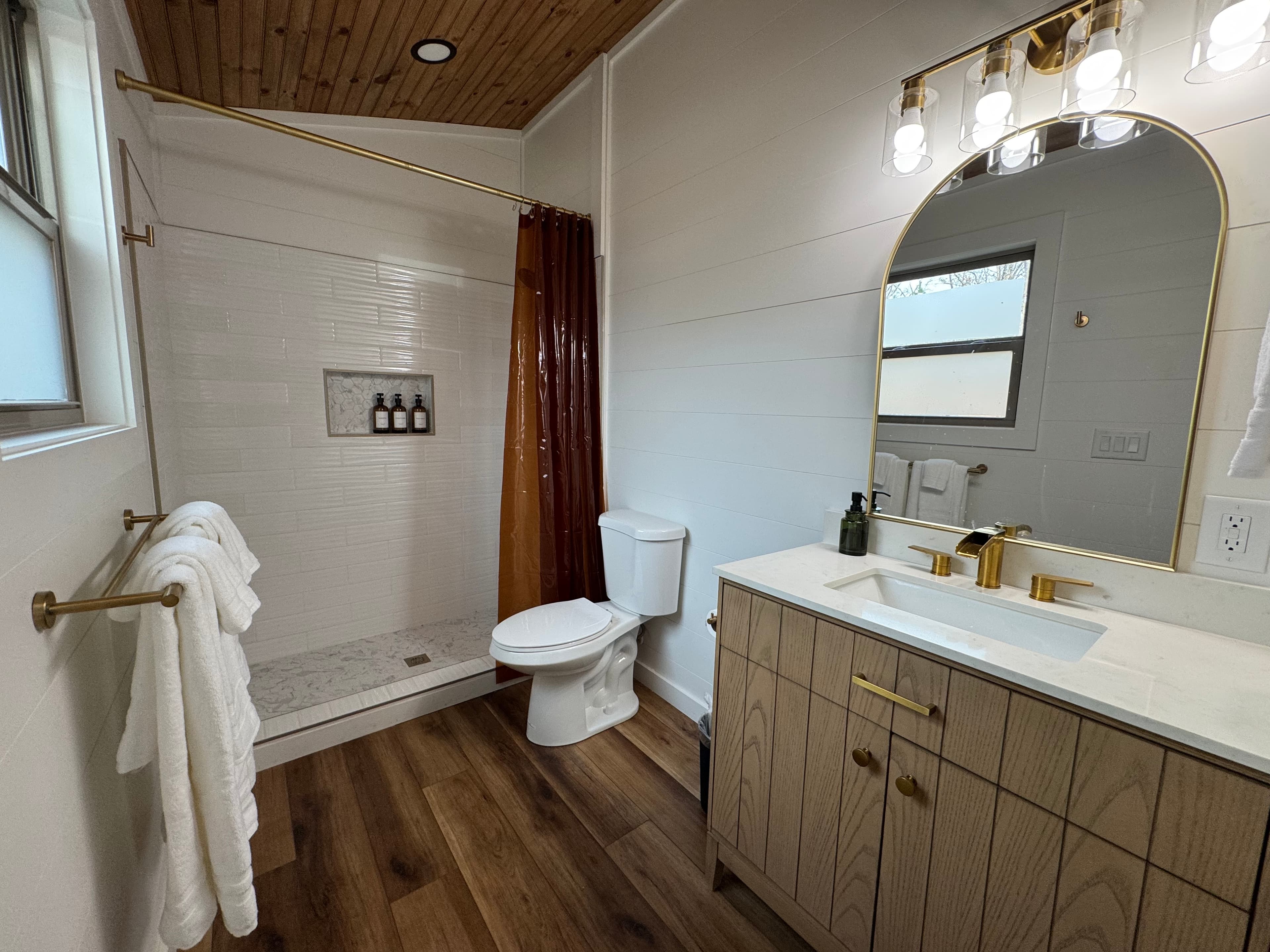Bathroom with walnut vanity and round black-framed mirror