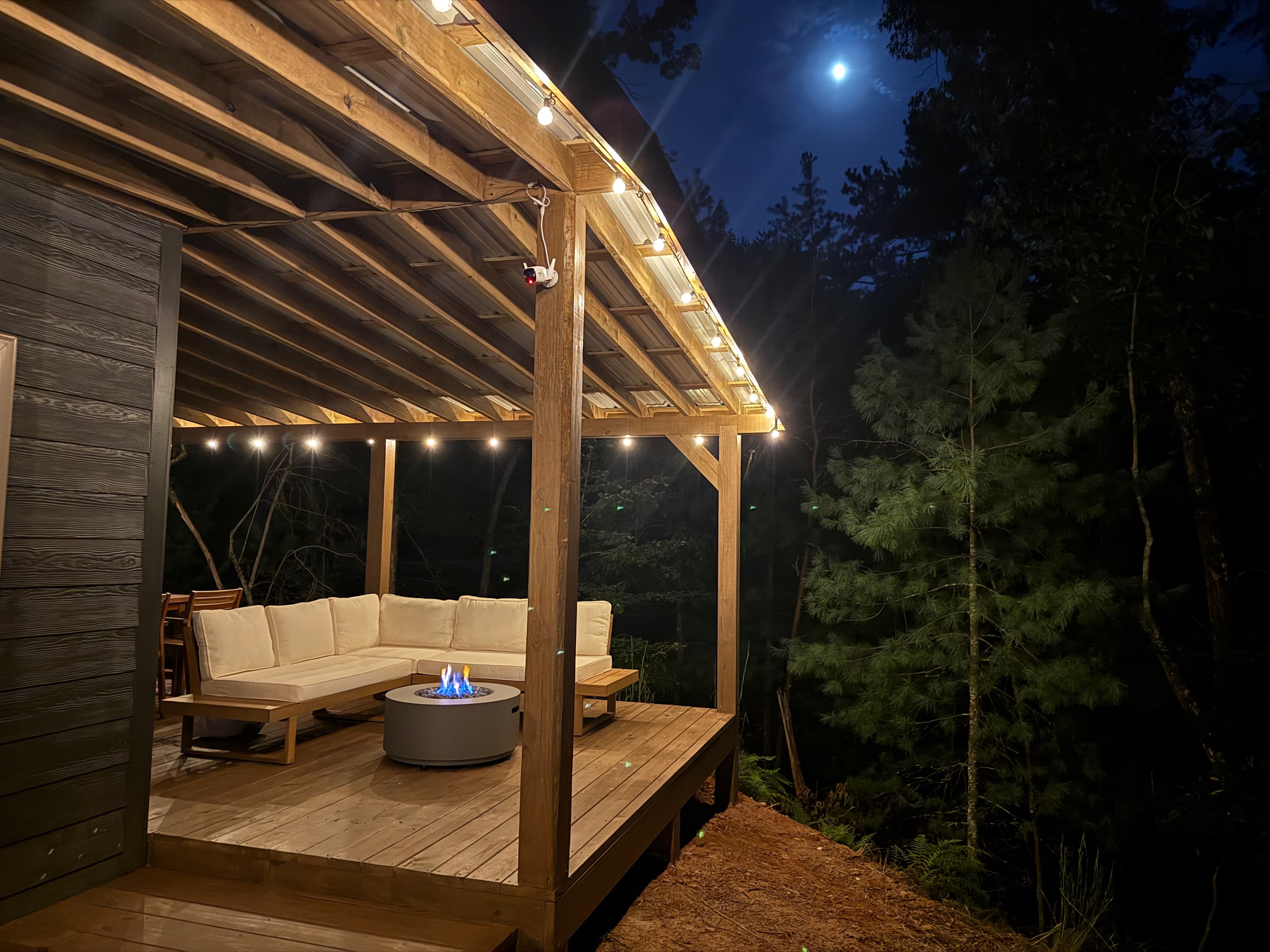 The pergola lounge with the fire pit lit at night