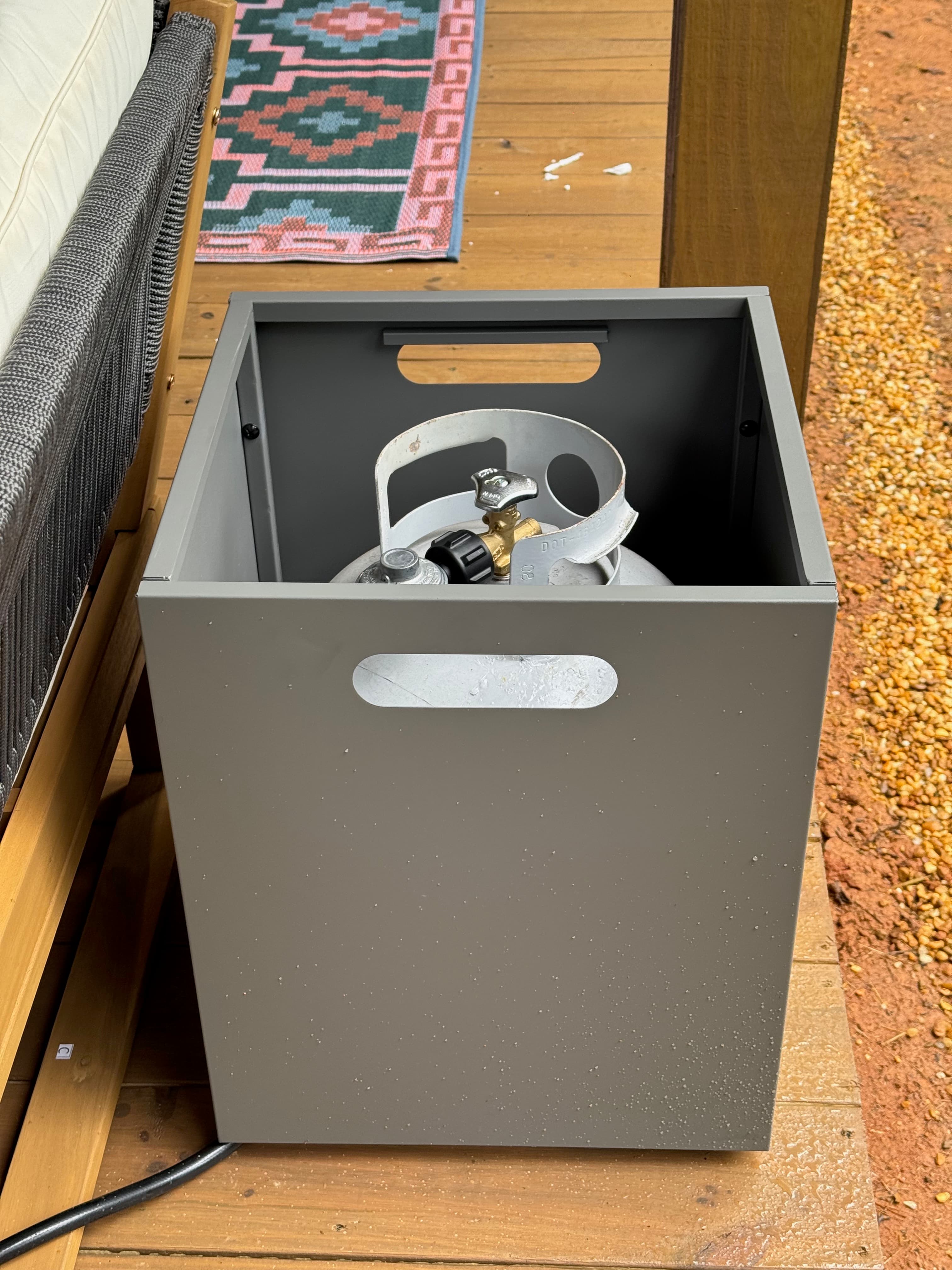 Propane tank stored in its box behind the outdoor sectional