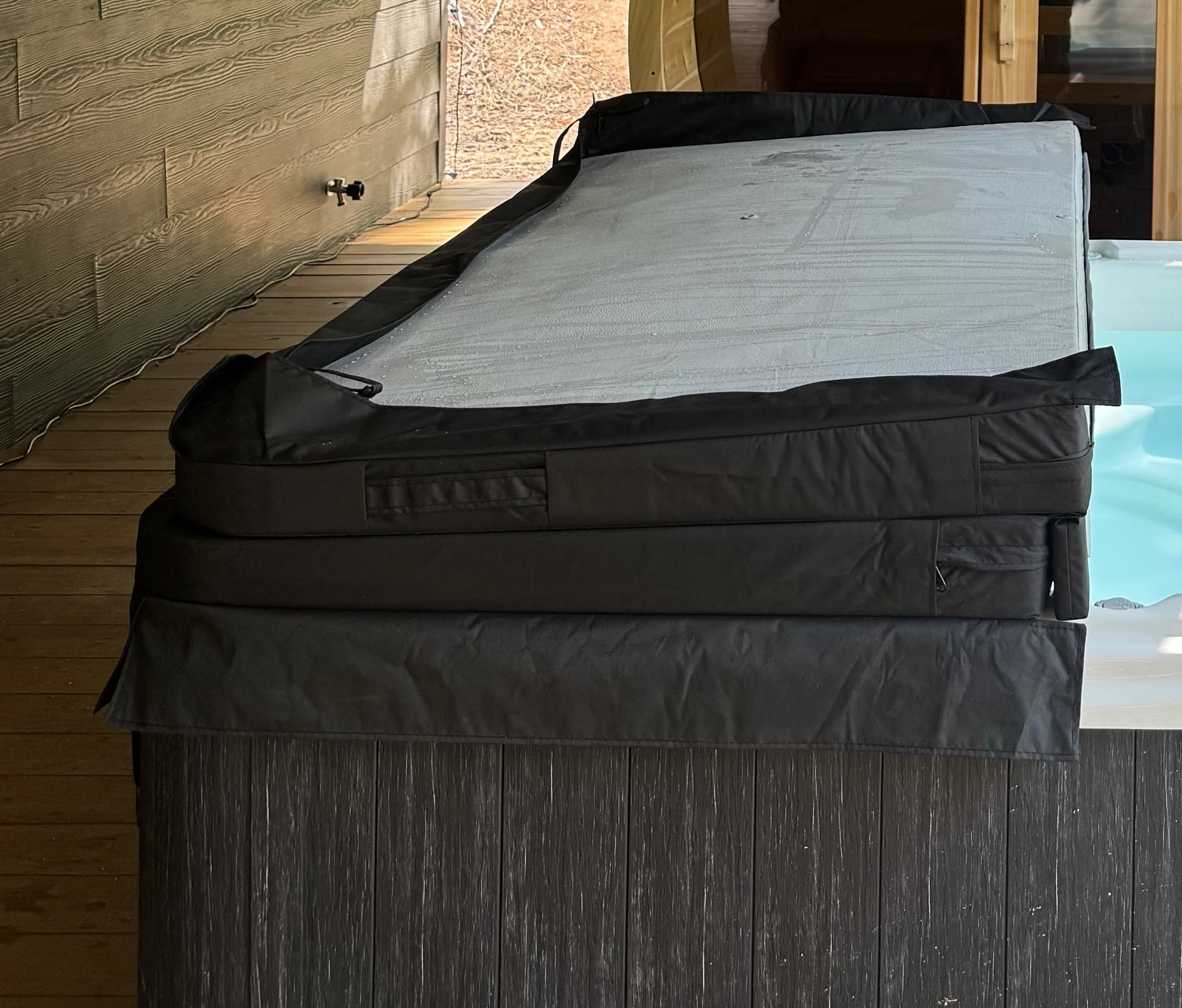 The hot tub cover folded in half and stacked on top of the tub